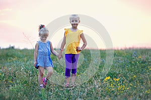 Two little girls laughing together on a summer walk in the countryside