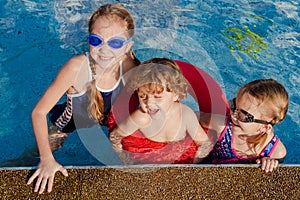 Two little girls and little boy playing in the pool