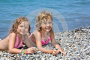 Two little girls lying on stony beach photo