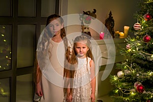 Two little girls near the christmas tree. Holidays, new year concept.