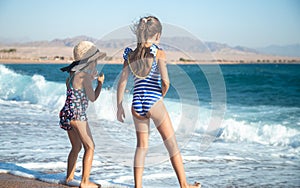 Two little girls play along the beach by the sea photo
