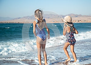 Two little girls play along the beach by the sea
