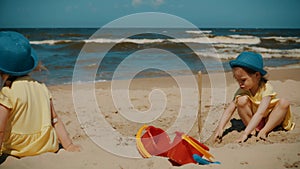 Two little girls play on the beach in summer