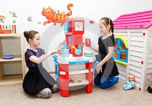 Two little girls play role game with toy kitchen in day care