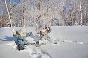 Two little girls play and throw up a snow in a winter