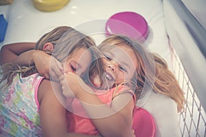 Two little girls in playground. Caucasian girls lying on floor a