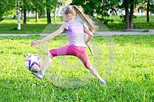 Two little girls playing with a ball on a green grass