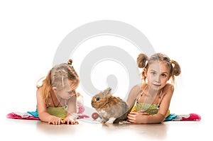 Two little girls playing with Easter bunny on a white background