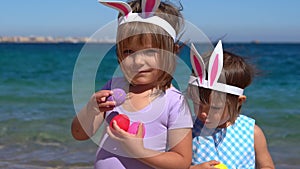 Two little girls playing with easter eggs on the beach