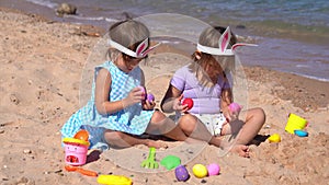 Two little girls playing with easter eggs on the beach