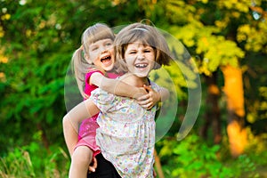 Two little girls playing fly in summer park.