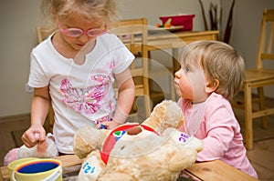 Two little girls playing together at home with plush toys