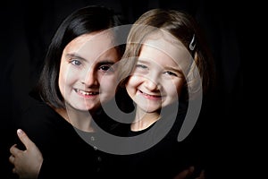 Two little girls posing on a black background