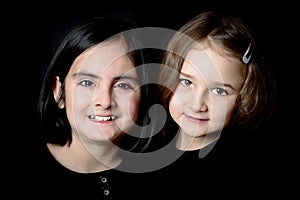 Two little girls posing on a black background
