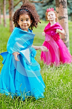 Two little girls in puffy gowns perform on grassy