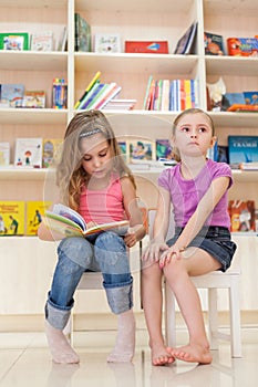 Two little girls are reading an interesting book