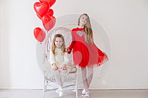 Two little girls with red balloons on Valentine`s Day