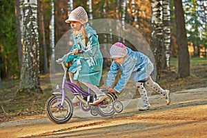 Two little girls riding toy cycle