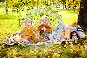 Two little girls sit on a blanket in the park sunlight. Children have a picnic in nature