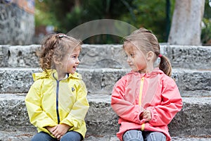 Two little girls sitting on the stairs, outside. Happy childhood