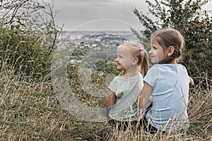 Two little girls sitting together in the tall grass