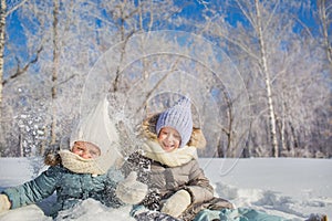 Two little girls smile and play with a snow in a winter