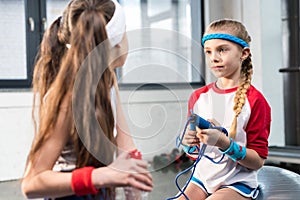 Two little girls in sportswear sitting at fitness studio