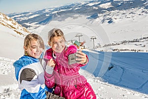 Two little girls taking selfie with phone in the snow