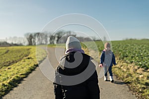 Two little girls walking on a country road in the countryside in winter