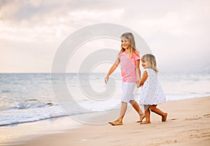 Two Little Girls Walking together on the Beach at Sunet