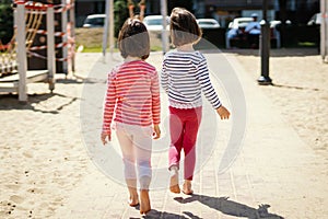 Two little girls are walking together on the playground
