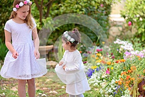 Two little girls in white dresses having fun a summer garden.