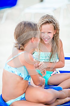 Two little happy girls have a lot of fun at tropical beach playing together