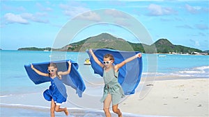 Two little happy girls have a lot of fun at tropical beach playing together