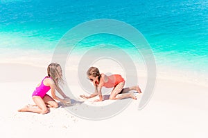 Two little happy girls have a lot of fun at tropical beach playing together