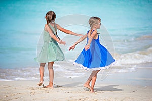 Two little happy girls have a lot of fun at tropical beach playing together