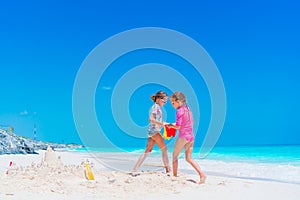 Two little happy girls have a lot of fun at tropical beach playing together