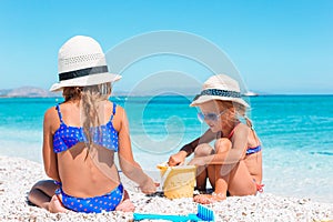 Two little happy girls have a lot of fun at tropical beach playing together