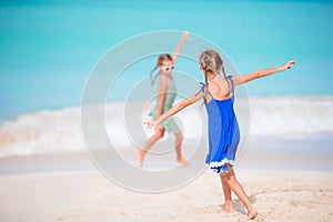 Two little happy girls have a lot of fun at tropical beach playing together