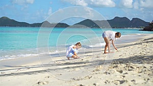 Two little happy girls have a lot of fun at tropical beach playing together with sand