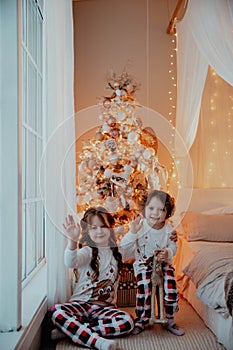 Two little happy girls in pijamas on christmas new year& x27;s eve