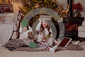 Two little happy girls in pijamas with gift boxes on christmas new year's eve