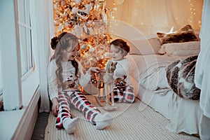 Two little happy girls in pijamas playing on christmas new year& x27;s eve