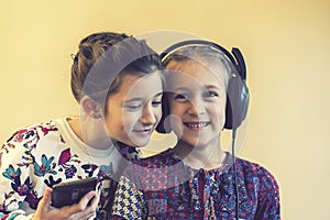Two little happy girls together listening to music. Two little girls laughing while listening to music. toned