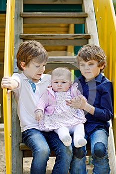 Two little happy kid boys with newborn baby girl, cute sister.