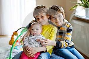 Two little happy kid boys with newborn baby girl, cute sister.