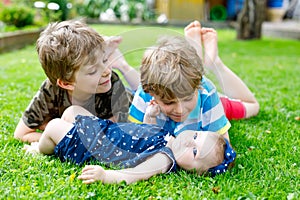 Two little happy kid boys with newborn baby girl, cute sister.