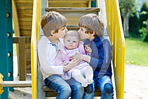 Two little happy kid boys with newborn baby girl, cute sister.