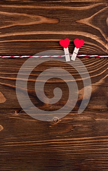 Two little hearts symbol of St. Valentine\'s day on a clothespin and string  copy space  flat lay on wooden background