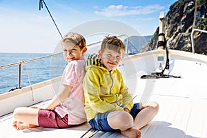 Two little kid boys, best friends enjoying sailing boat trip. Family vacations on ocean or sea on sunny day. Children